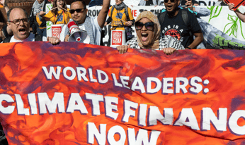 people holding a banner that says "World Leaders: Climate Finance Now"