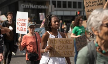 a woman holds a sign in protest of fossil fuels