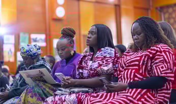 women seated during a meeting, taking notes