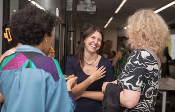 a woman smiling as she speaks with others