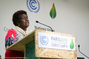 a woman stands at a podium during COP21, addressing a crowd