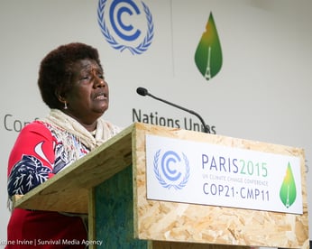 a woman stands at a podium during COP21, addressing a crowd